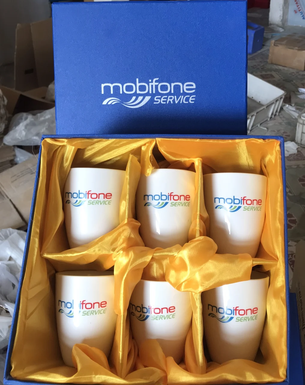 Hộp xanh lót vàng chứa sáu cốc in logo MobiFone Service