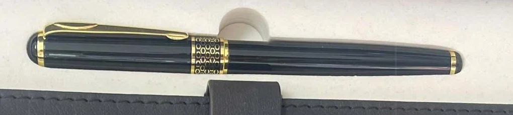 Bút đen có kẹp và viền vàng trong hộp sổ xám