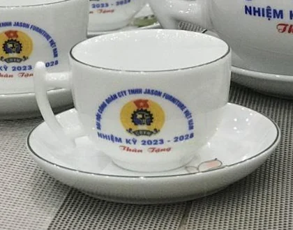 Chén trắng in logo khách đặt trên đĩa kê họa tiết sen