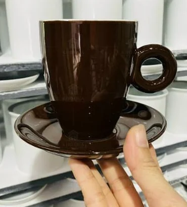 Cốc Latte màu nâu có quai tròn đặt trên đĩa kê