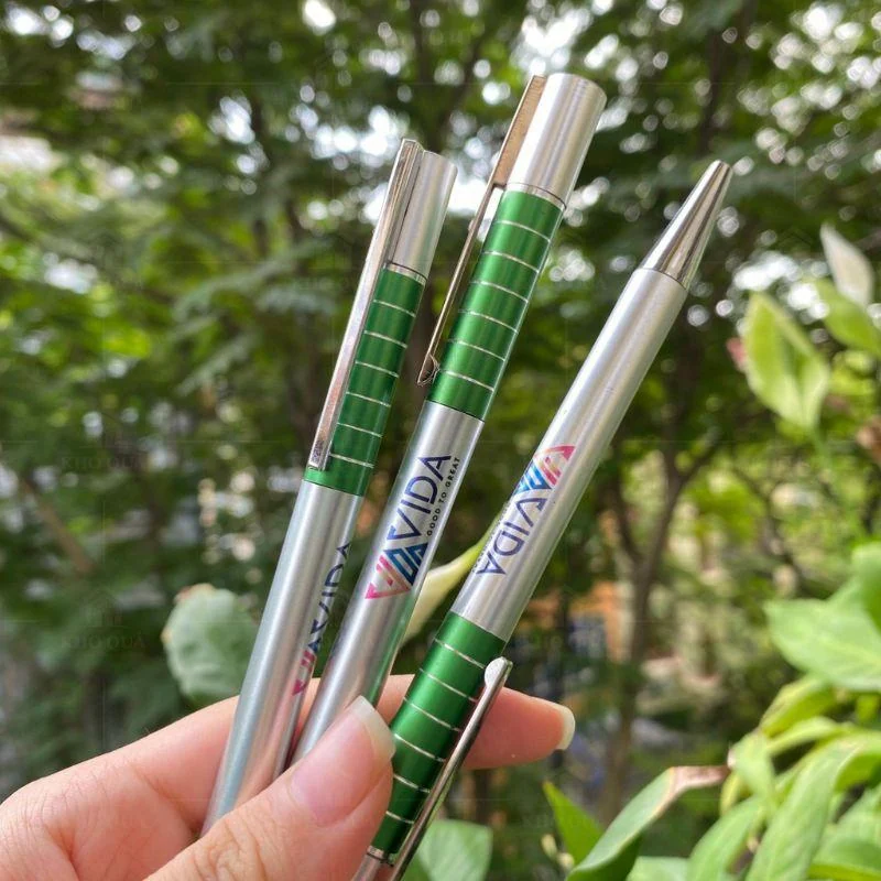 Ba bút xanh lá và bạc in nhận diện VIDA được cầm trên tay