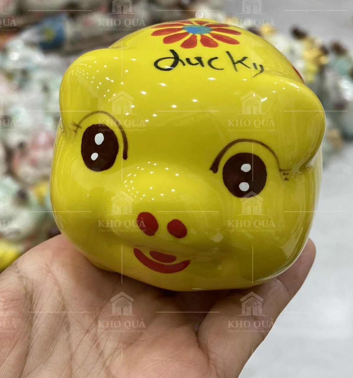 Heo đất vàng có chữ Lucky và hoa được cầm trên tay