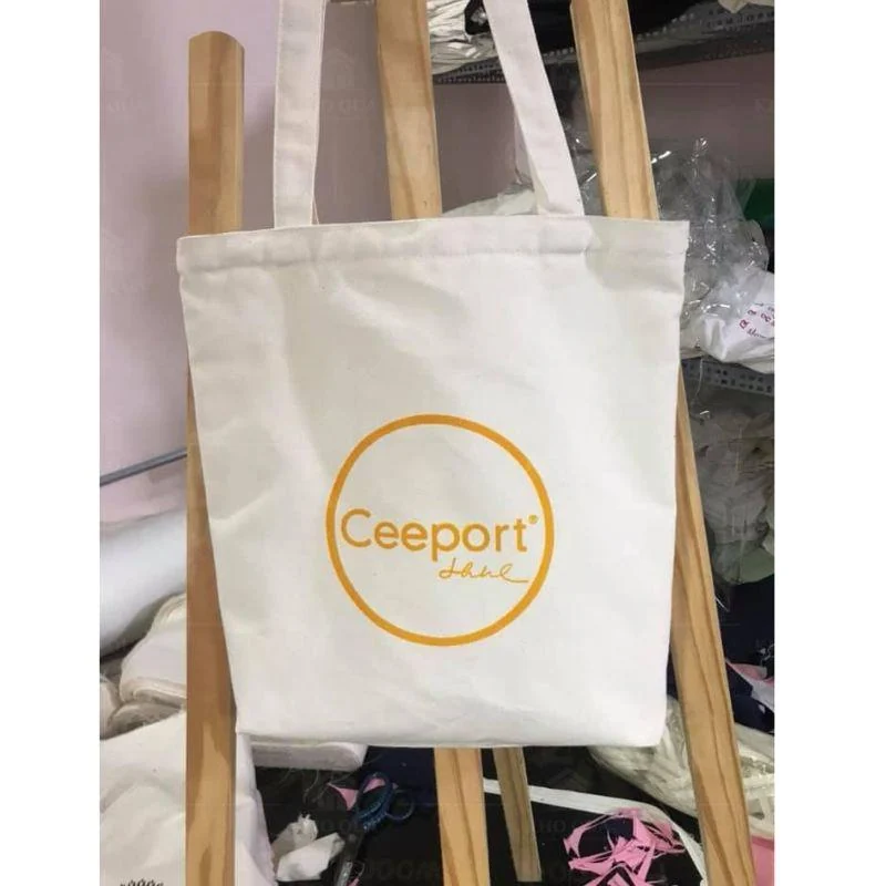 Túi canvas màu kem in Ceeport treo trên giá gỗ trong gallery túi canvas CV01