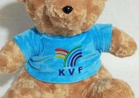Góc cận áo xanh gấu bông với logo KVF và phần thân gấu
