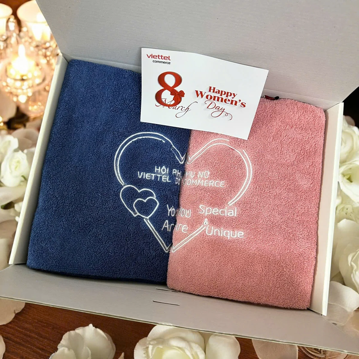 Hai khăn xanh và hồng có hình thêu và chữ trải qua hai phần trong hộp